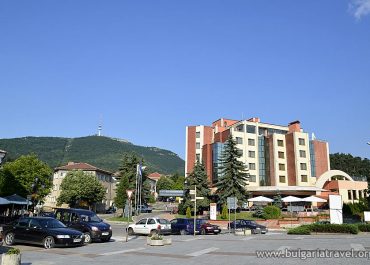 A large building with a parking lot in front and a mountain in the background.