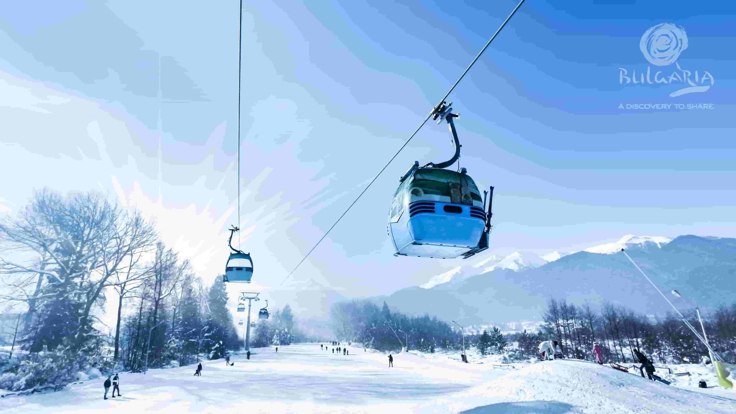 A ski lift carrying people up a snowy mountain, surrounded by a picturesque winter landscape.