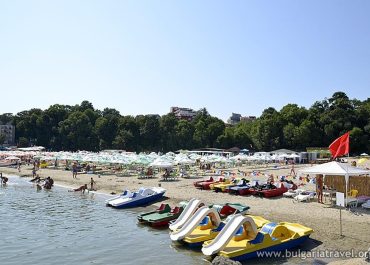 A crowded beach with numerous boats and people enjoying the sunny day by the sea.