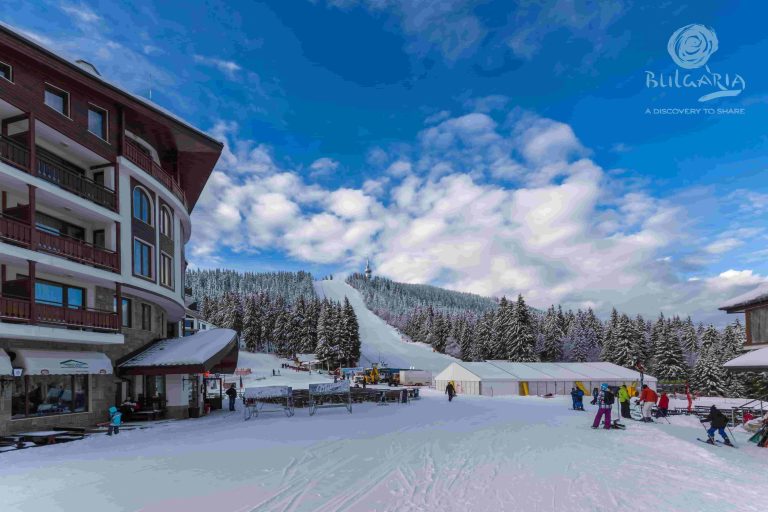 A ski resort with skiers and snowboarders enjoying the slopes on a sunny day.