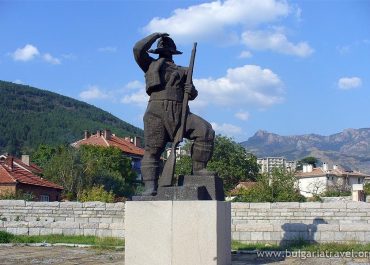Military statue with rifle against mountain backdrop