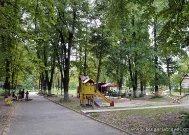 A park with a playground equipment and lush trees in the background.