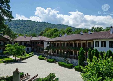 A spacious courtyard with trees and mountains in the background, enhancing the grandeur of the large building.